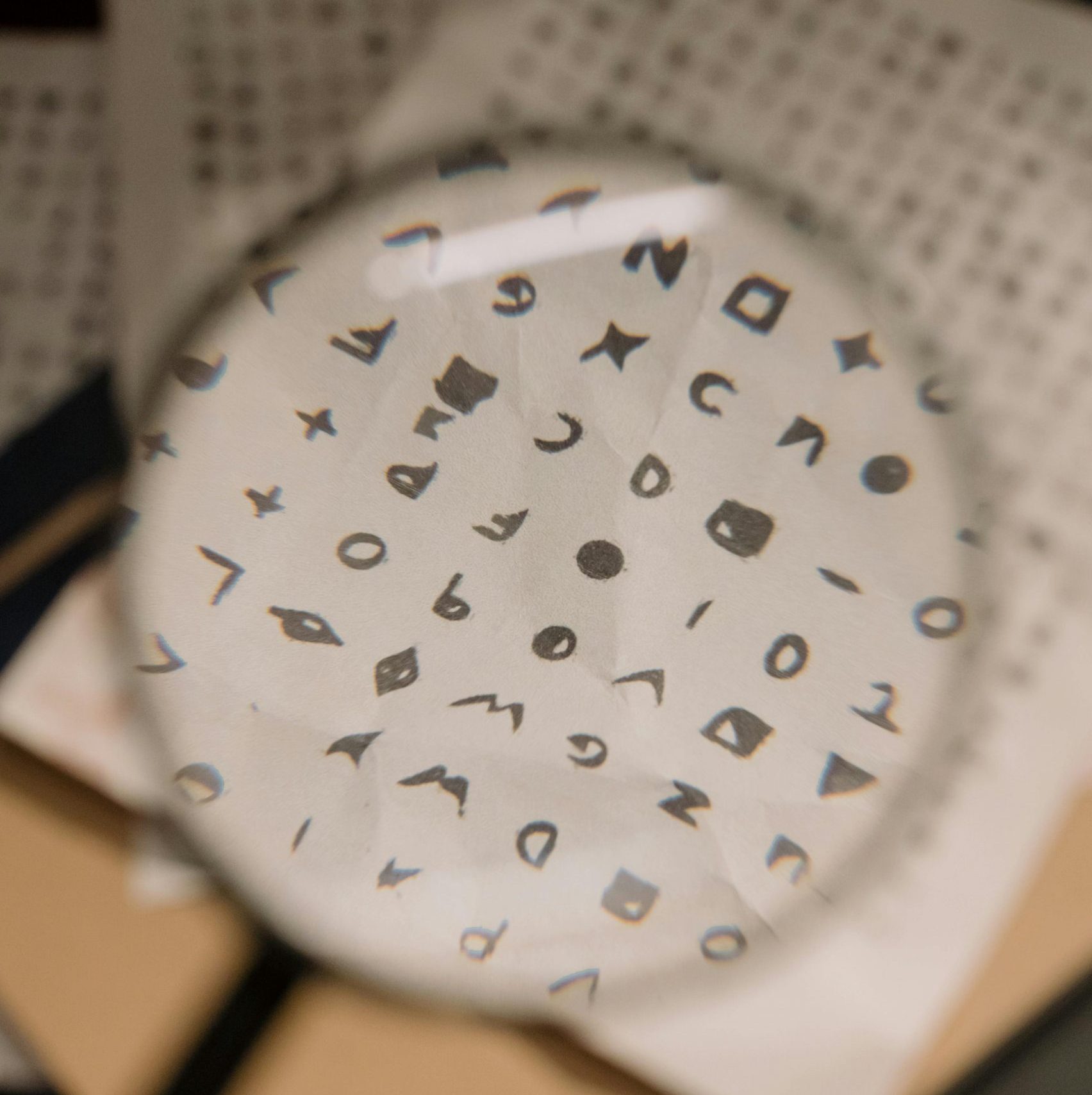 Magnifying glass revealing cryptic symbols on paper, ideal for mystery themes.