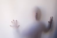 Eerie silhouette of a person pressing against a white curtain, creating a mysterious atmosphere.